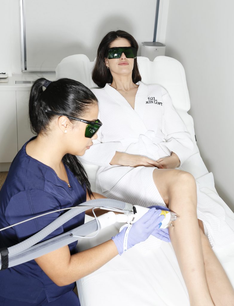 Licensed technician performing laser hair removal on a woman's legs using advanced equipment at Skin Loft clinic in New York