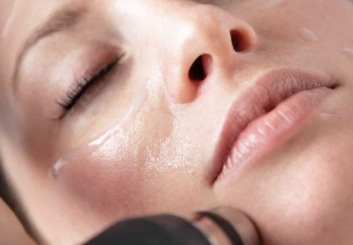 closeup of a woman with glowing skin receiving a facial treatment using an Oxypod device on her cheek