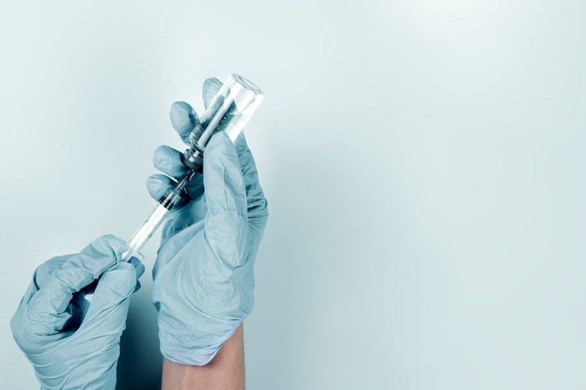 gloved hands drawing medication from vial for weight loss injection